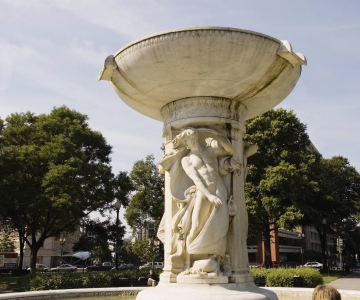 A statue of a woman or man in the middle of a circular fountain