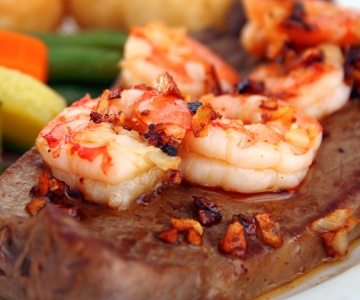 Shrimp served on top of a juicy steak
