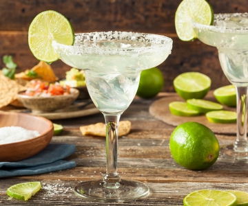 A margarita served with a lime in a tall cocktail glass